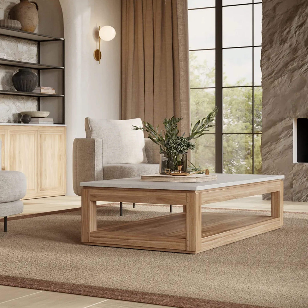 Modern living room featuring a timber coffee table with a white stone top, styled with a vase of greenery, an open book, and a brass candle holder.