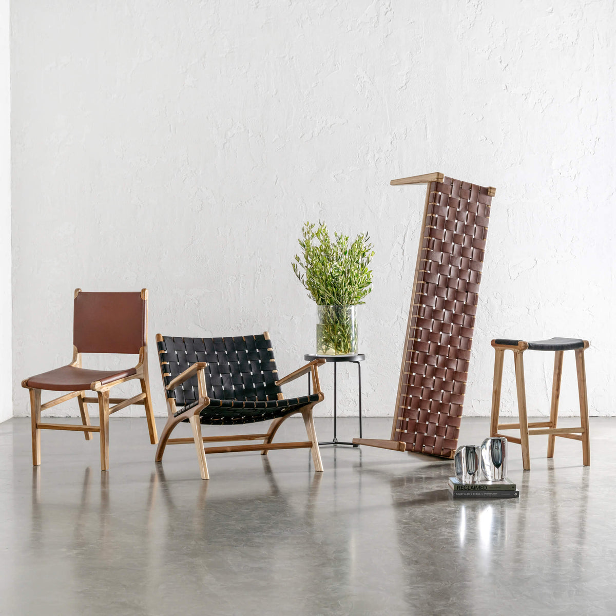 Grouping of timber furniture with woven leather detailing, including a brown dining chair, black lounge chair, black stool, and a tall brown woven screen or bedhead.